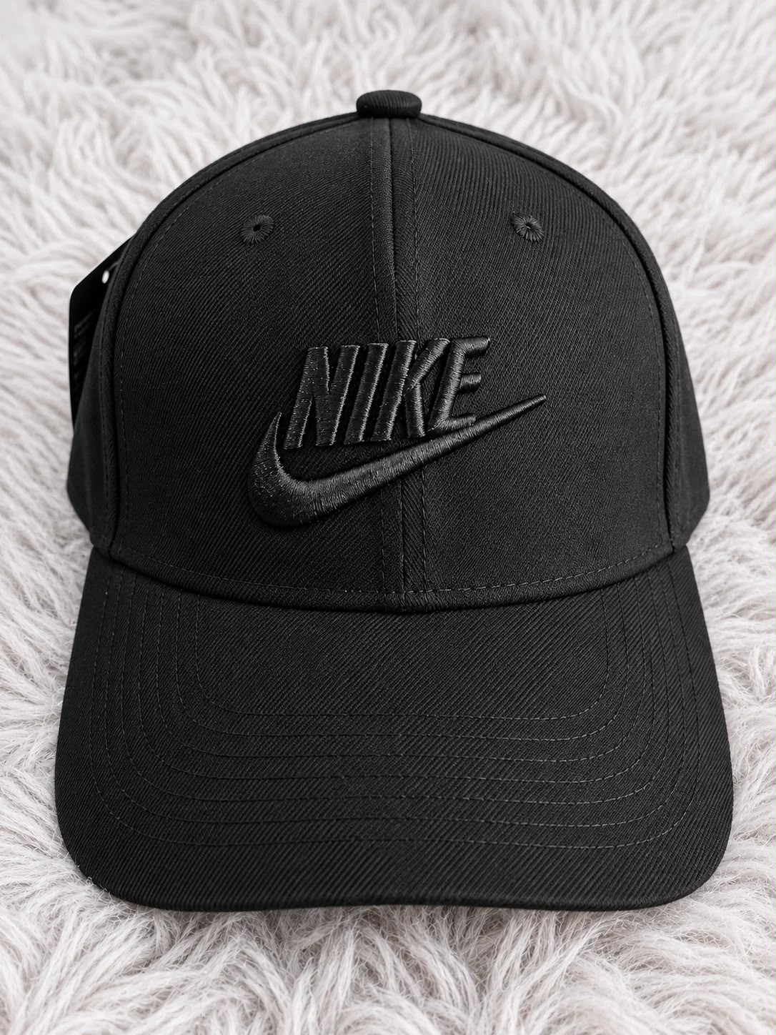 Gorra negra con nombre Nike y Swoosh bordados en negro, vista frontal