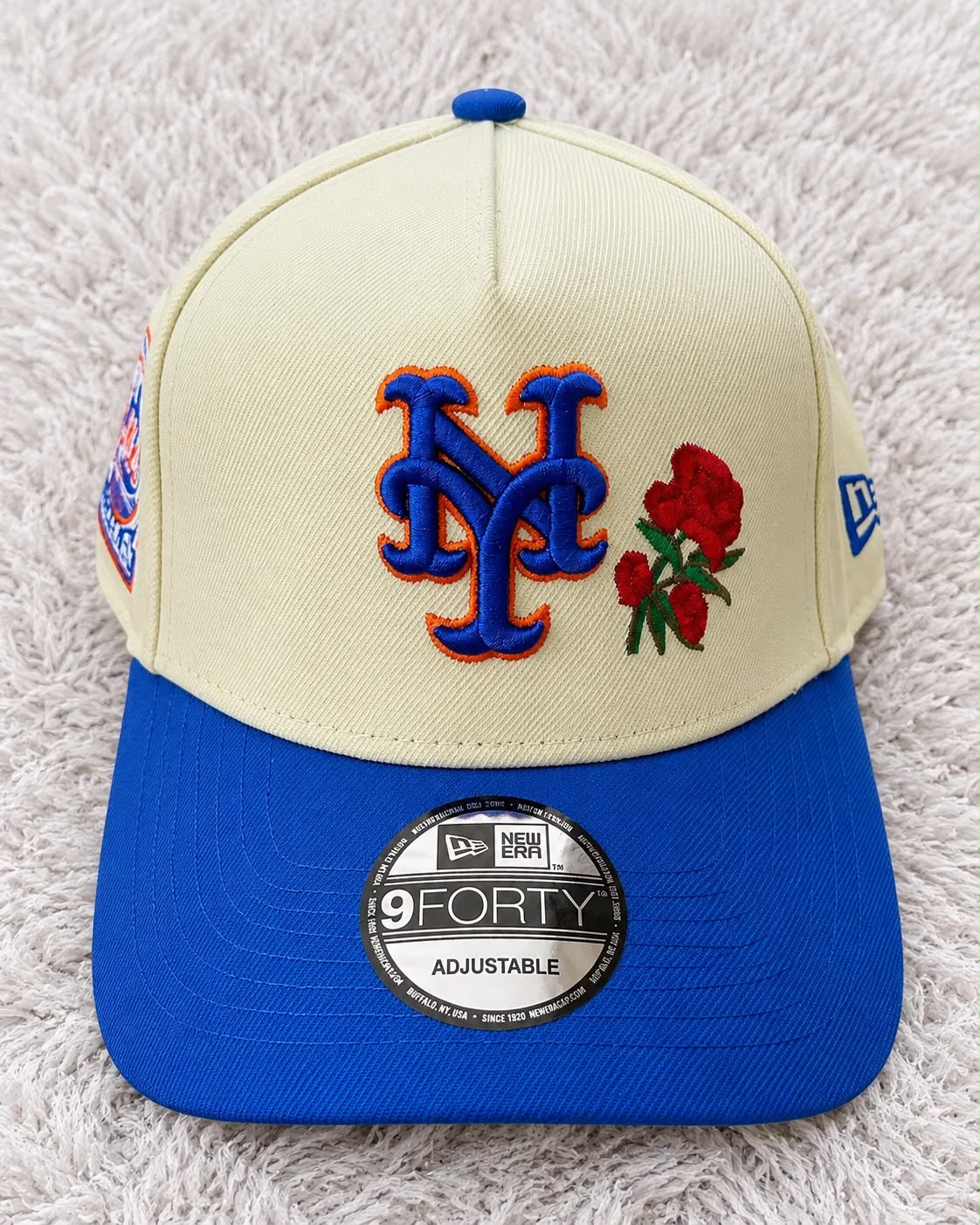 Gorra crema con visera azul, bordado NY azul con contorno naranja y rosas rojas al frente