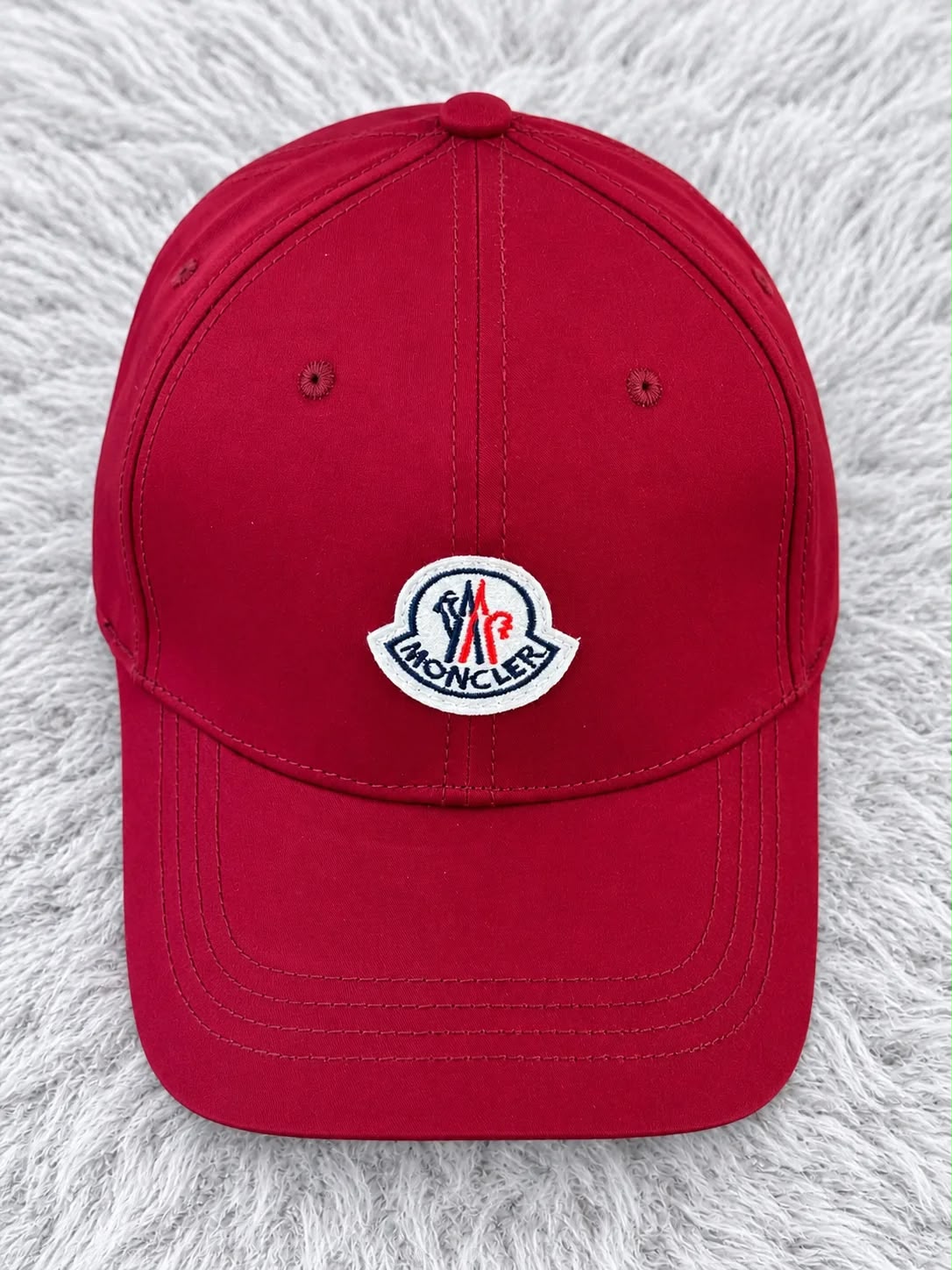 Gorra roja con parche blanco Moncler al frente y visera curva, vista frontal