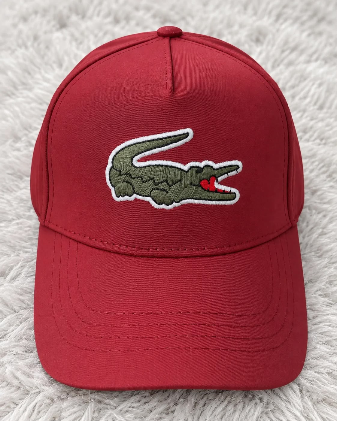 Gorra roja con cocodrilo verde bordado y contorno blanco al frente, con visera curva