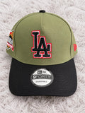 Gorra LA verde olivo con visera negra, bordado negro con contorno blanco y rojo y parche lateral