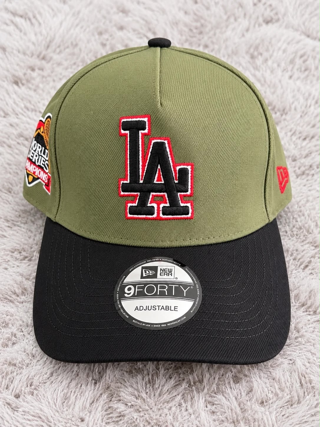 Gorra LA verde olivo con visera negra, bordado negro con contorno blanco y rojo y parche lateral
