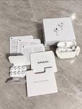 Audífonos blancos con estuche abierto, caja, documentación y almohadillas adicionales